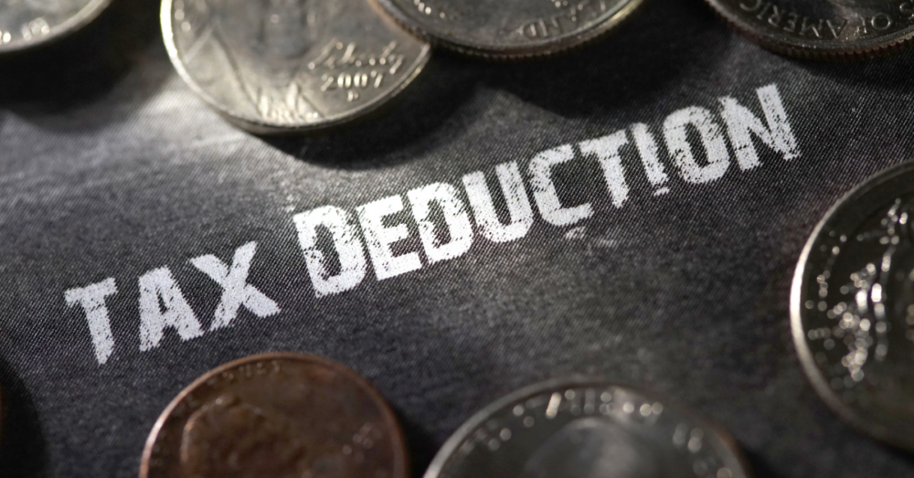 Tax deduction in chalk surrounded by us coin currency