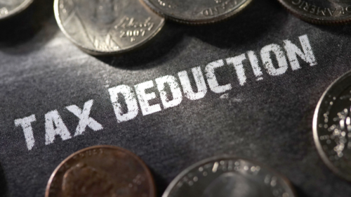 Tax deduction in chalk surrounded by us coin currency